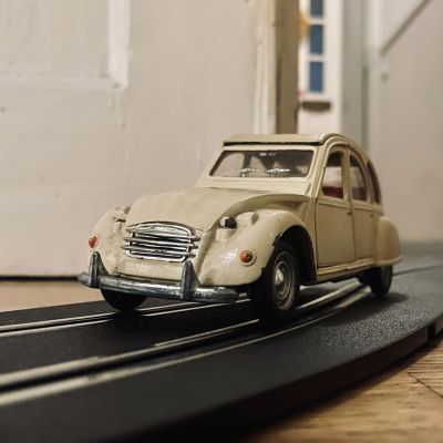 Ein altes Modellauto eines Citroen 2CV "Ente" in gelb.